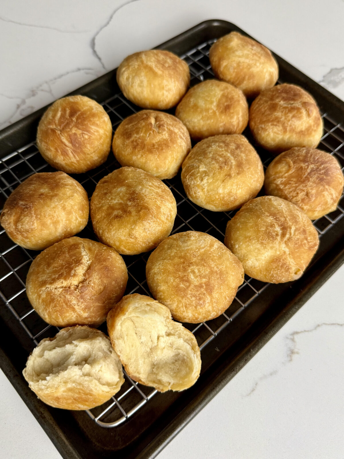 A tray of evenly fried Jamaican dumplings resting on a wire rack, showing their golden brown, slightly crisp exterior.