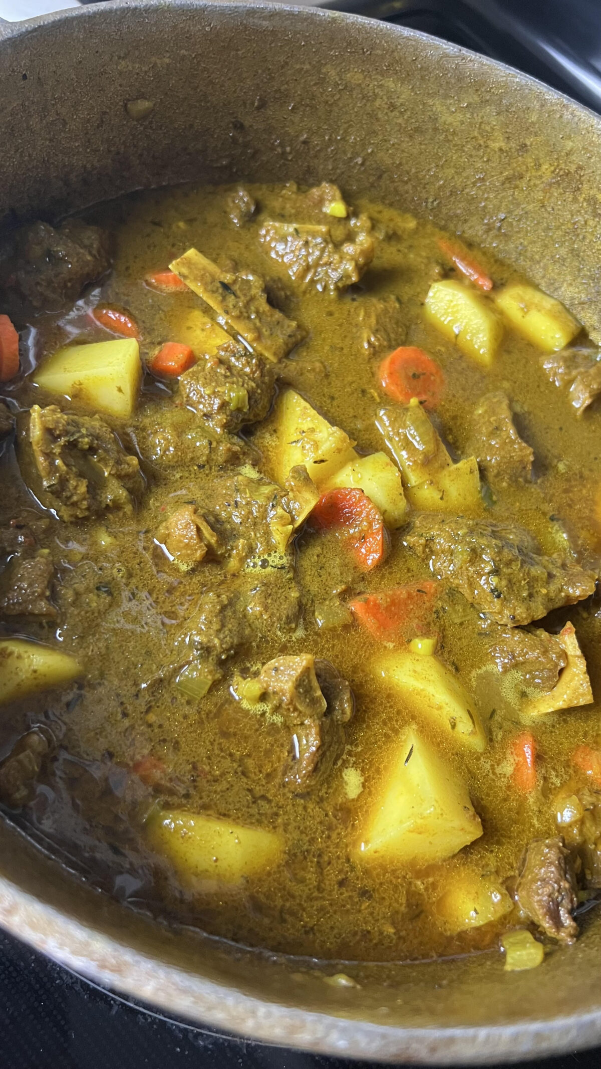 A Dutch oven full of Jamaican curry goat.