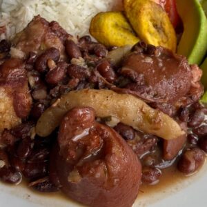 Close-up of Jamaican stew peas made with red beans, salted pigtail, and spinners in a rich broth.