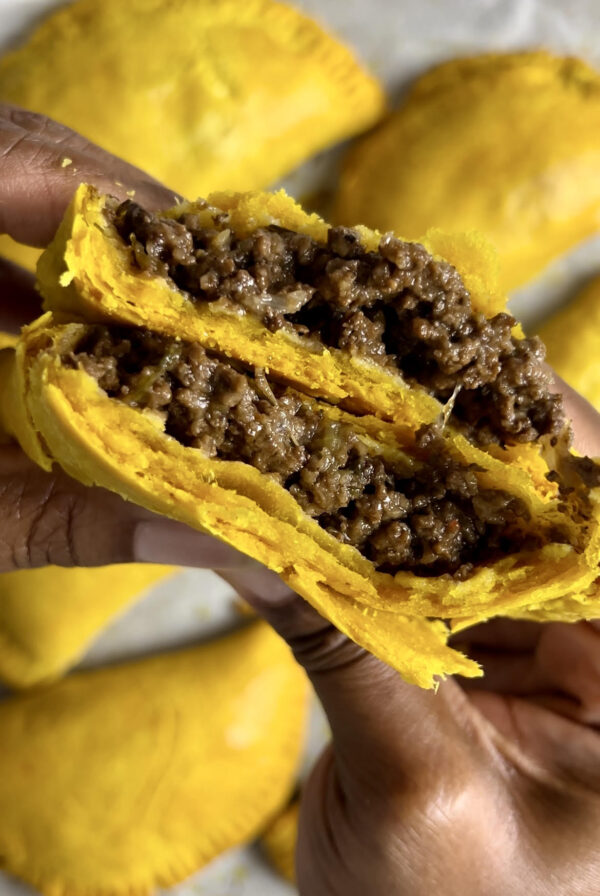 Delicious Jamaican beef patty split in half revealing its flakey layers and juicy beef filling.