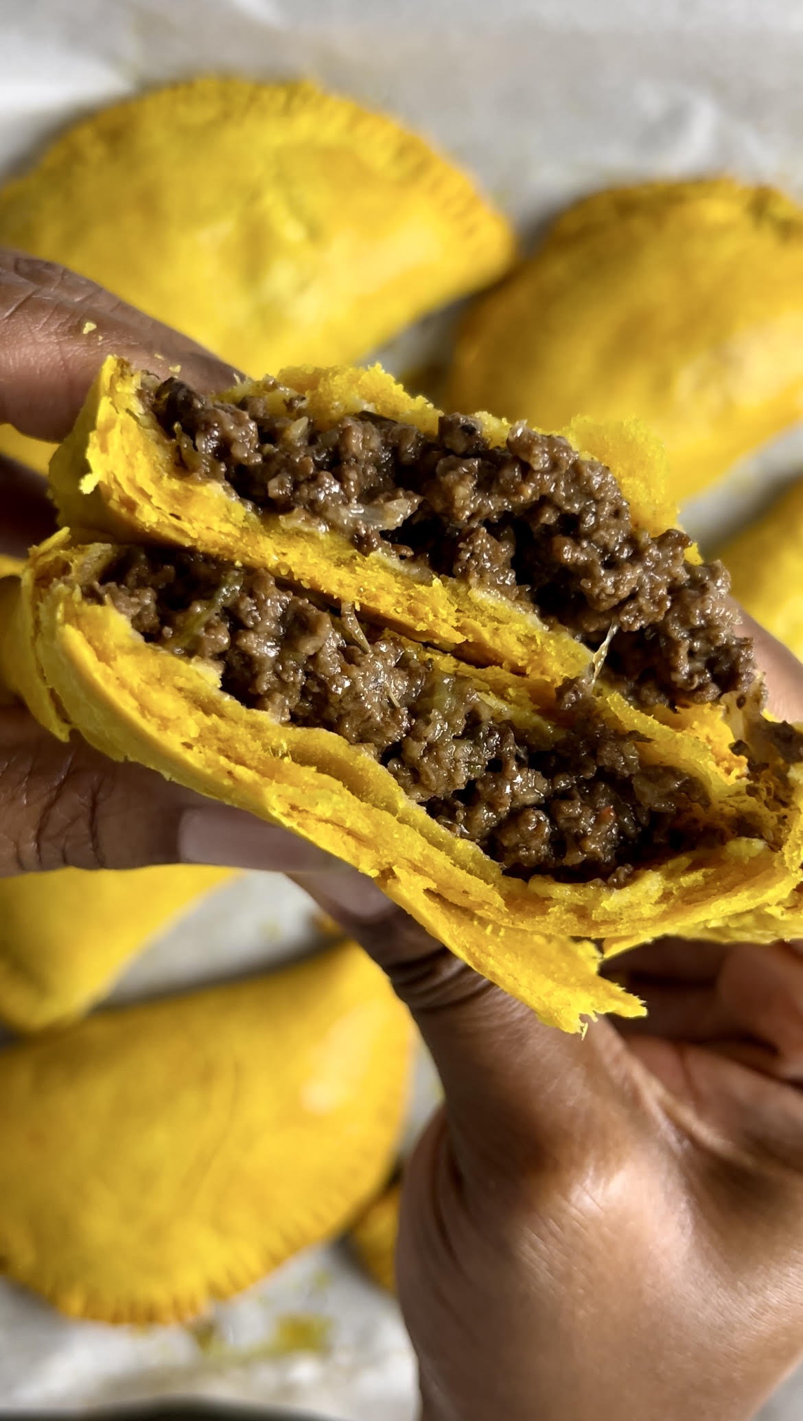 Delicious Jamaican beef patty split in half revealing its flakey layers and juicy beef filling.