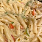 Close-up of Jamaican Rasta Pasta with penne and sliced red and green bell peppers coated in a creamy sauce.