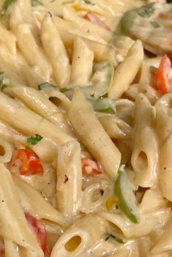 Close-up of Jamaican Rasta Pasta with penne and sliced red and green bell peppers coated in a creamy sauce.