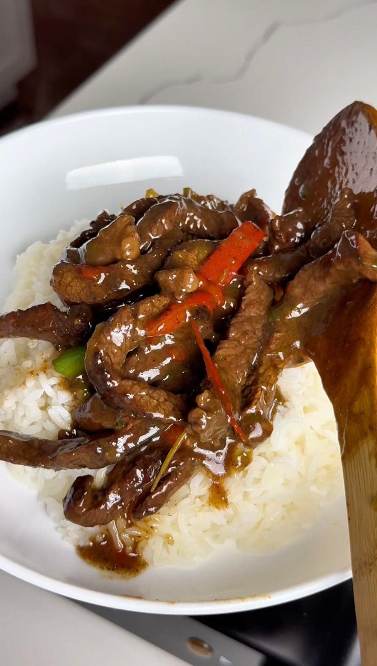 Pepper steak being served on a bed of white rice