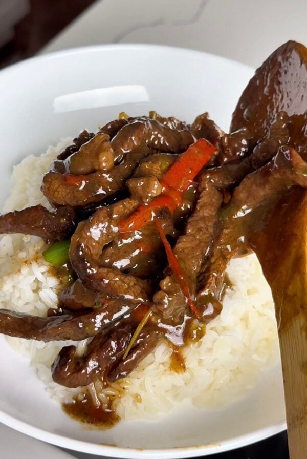 Pepper steak being served on a bed of white rice