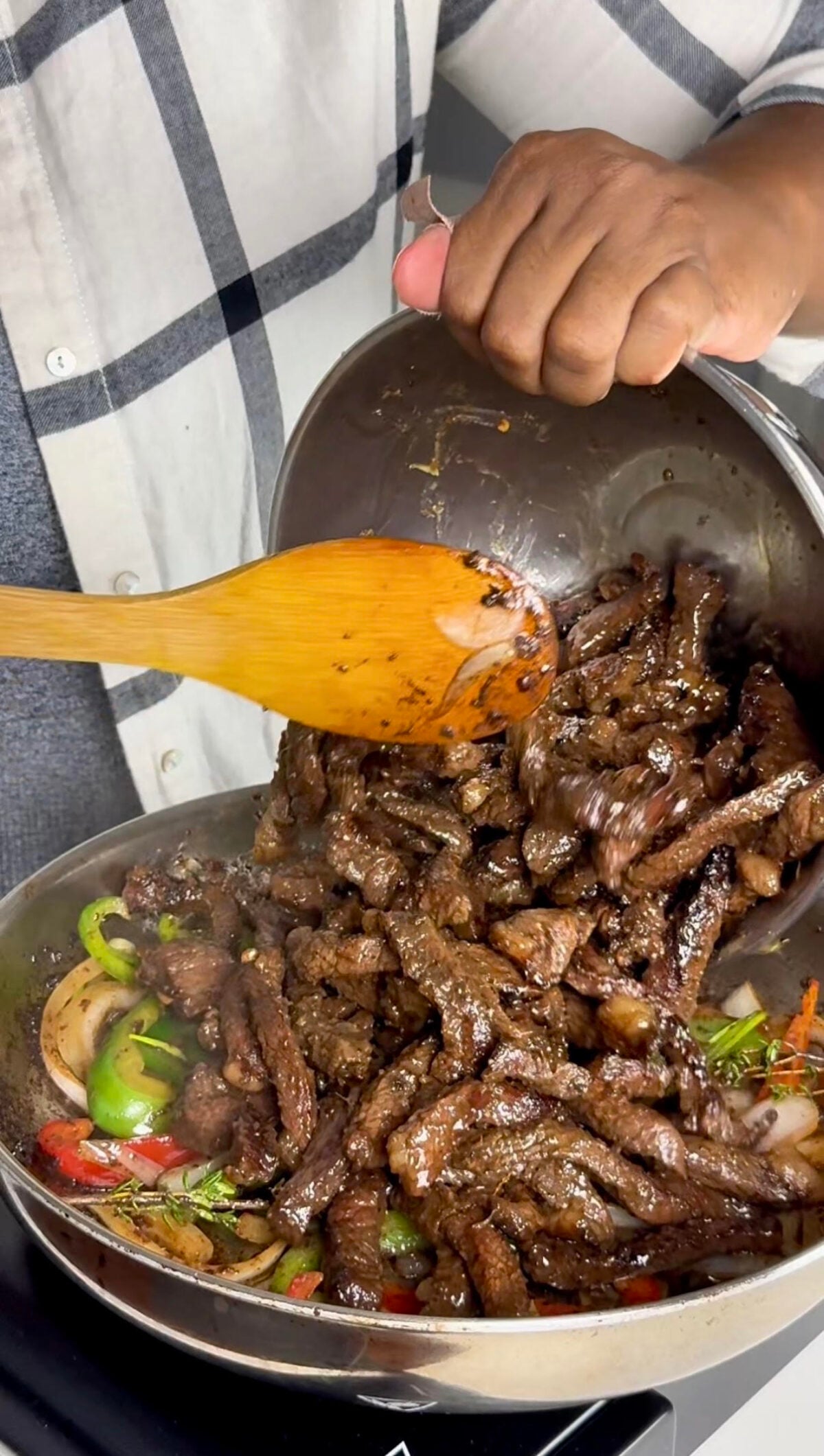 Seared steak strips get added to peppers and onions in a hot skillet.