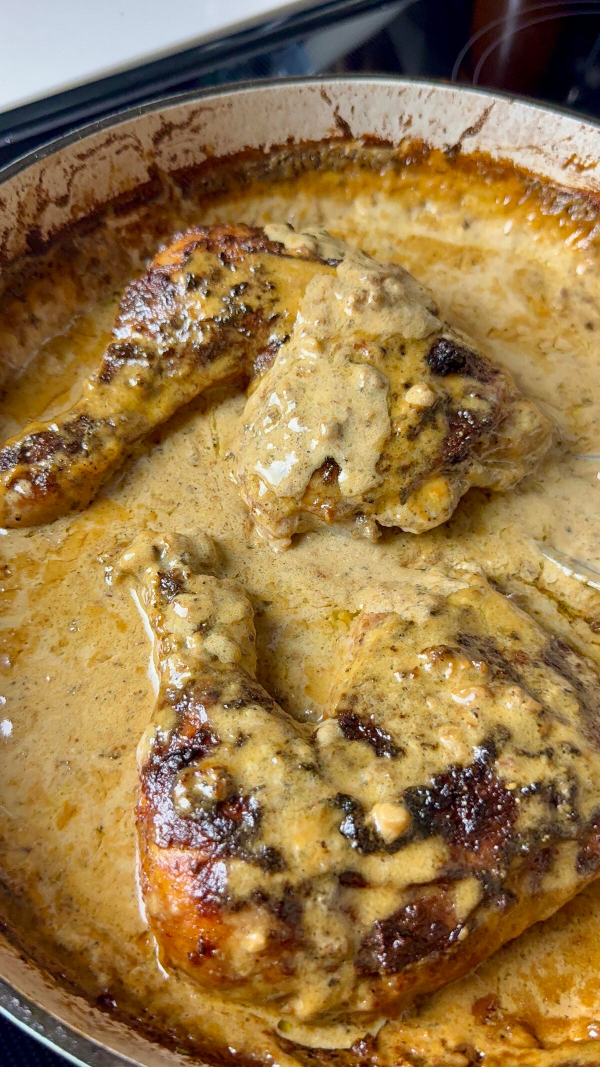 Chicken au poivre in a pan with plenty of creamy black pepper sauce.